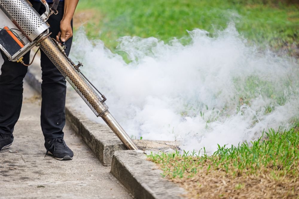 A person operates a hose to disperse a smoky substance during a mosquito control service in Renton, WA.